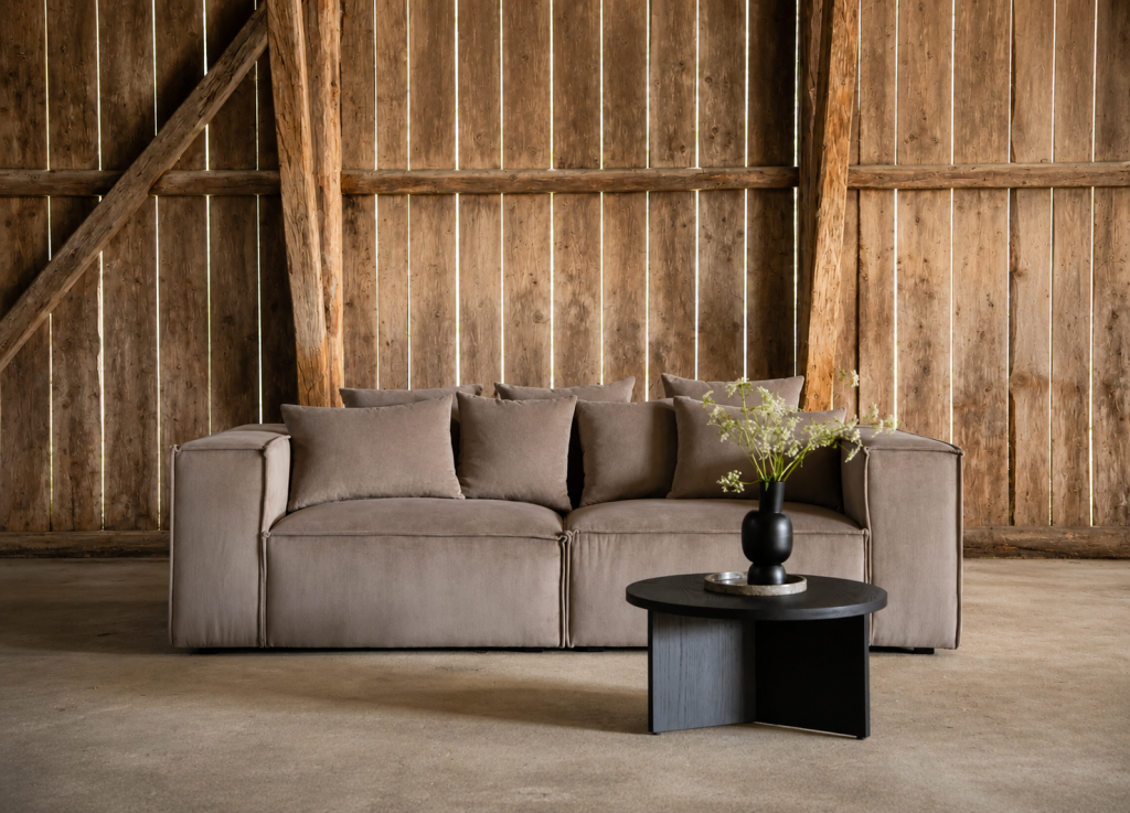 Canapé taupe en tissu avec table basse noire dans une ambiance rustique