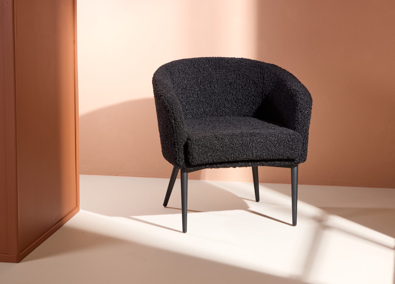 Fauteuil Fluffy en tissu teddy noir mis en scène dans un salon