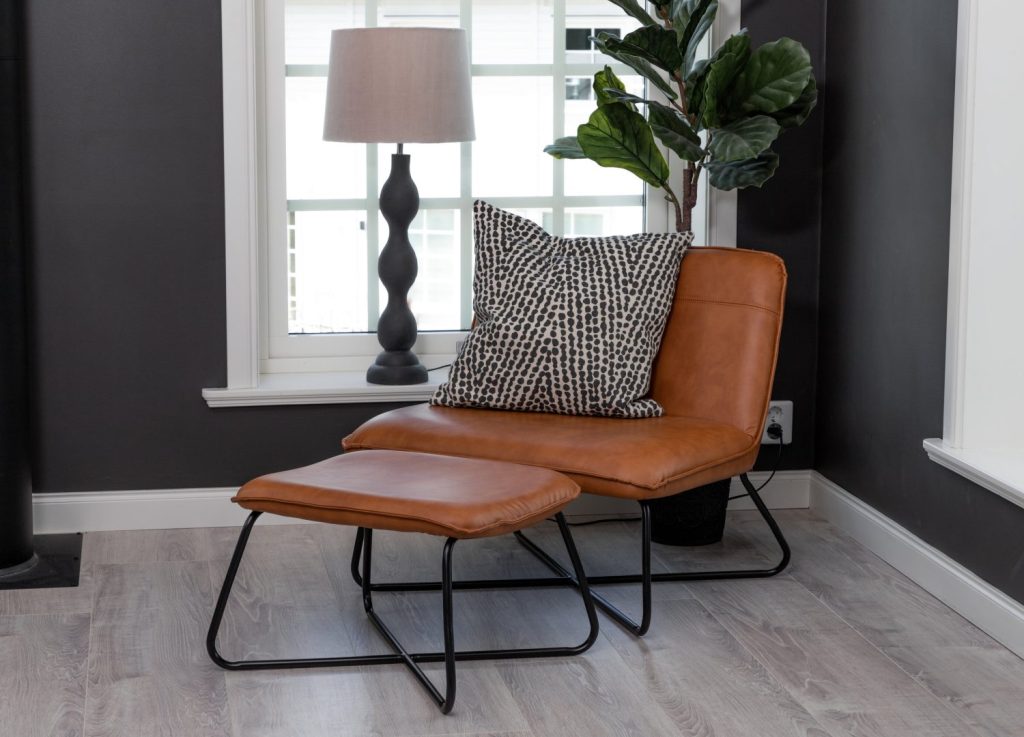 Fauteuil X en similicuir marron mis en scène dans un salon