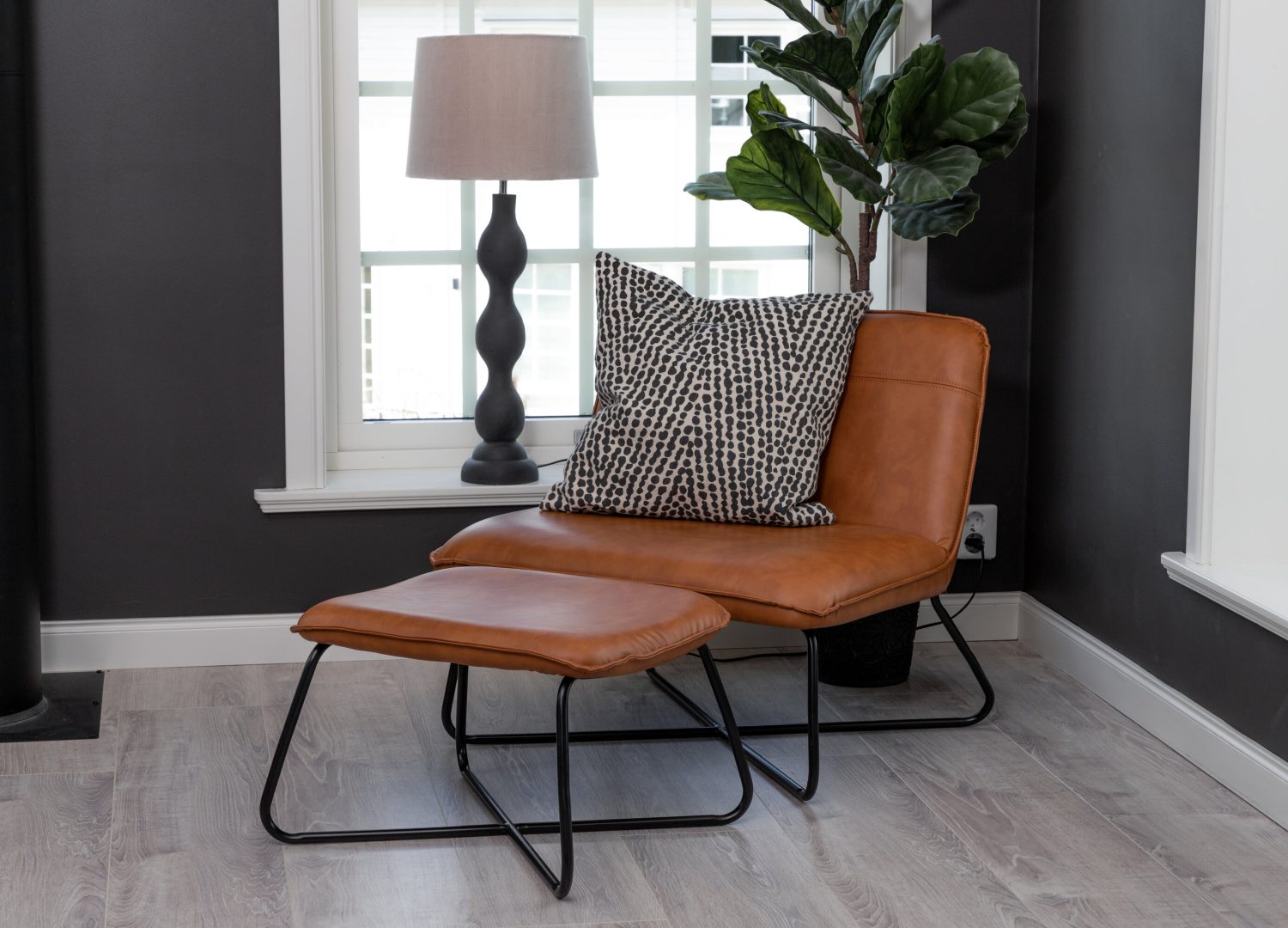 Fauteuil X en similicuir marron mis en scène dans un salon