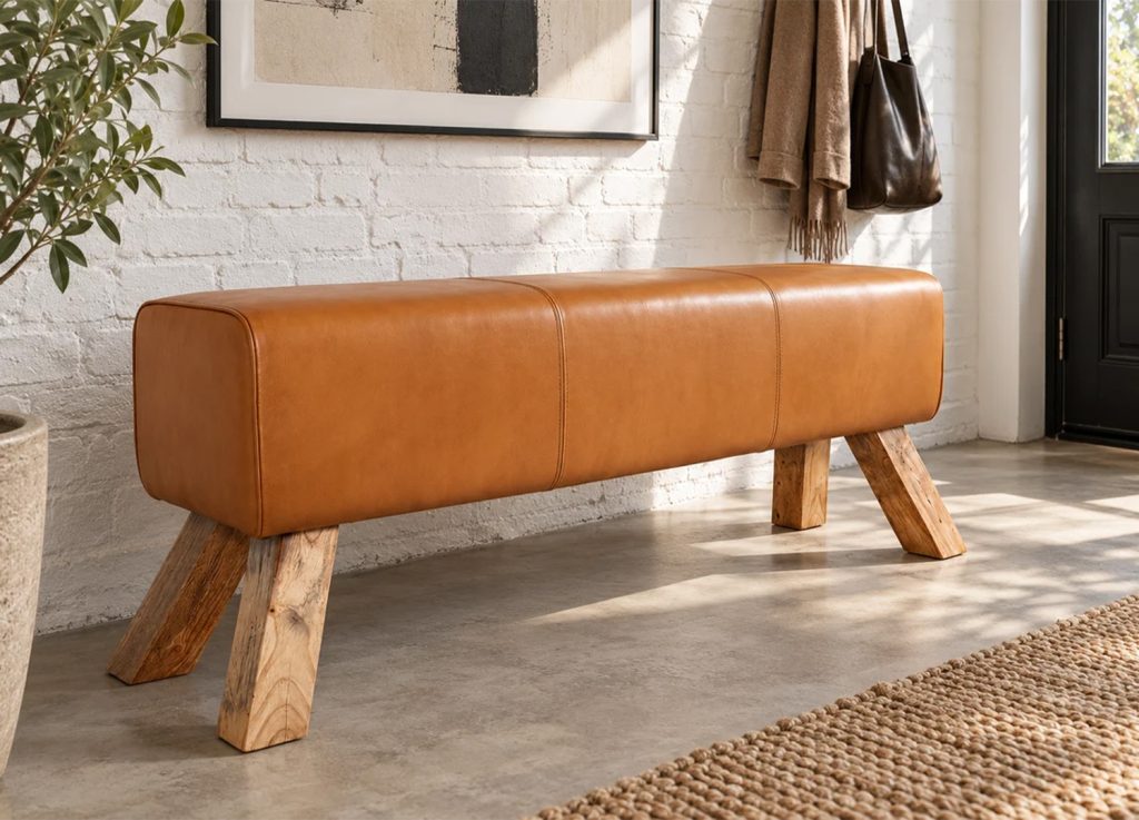 Banc CALVEO en cuir cognac avec piètement incliné en bois dans une entrée lumineuse