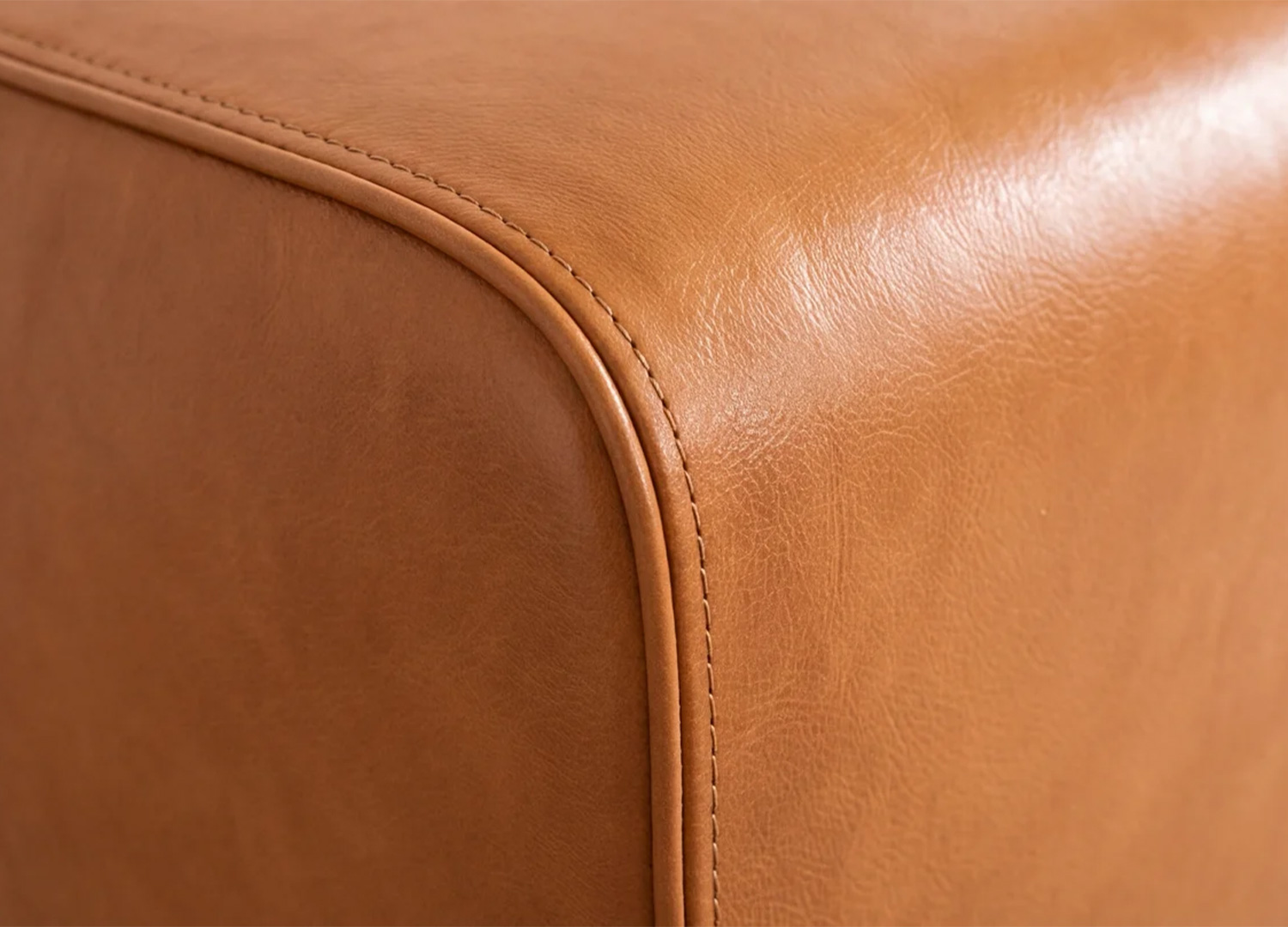 Gros plan sur le grain du cuir cognac et les coutures de l’assise du banc CALVEO