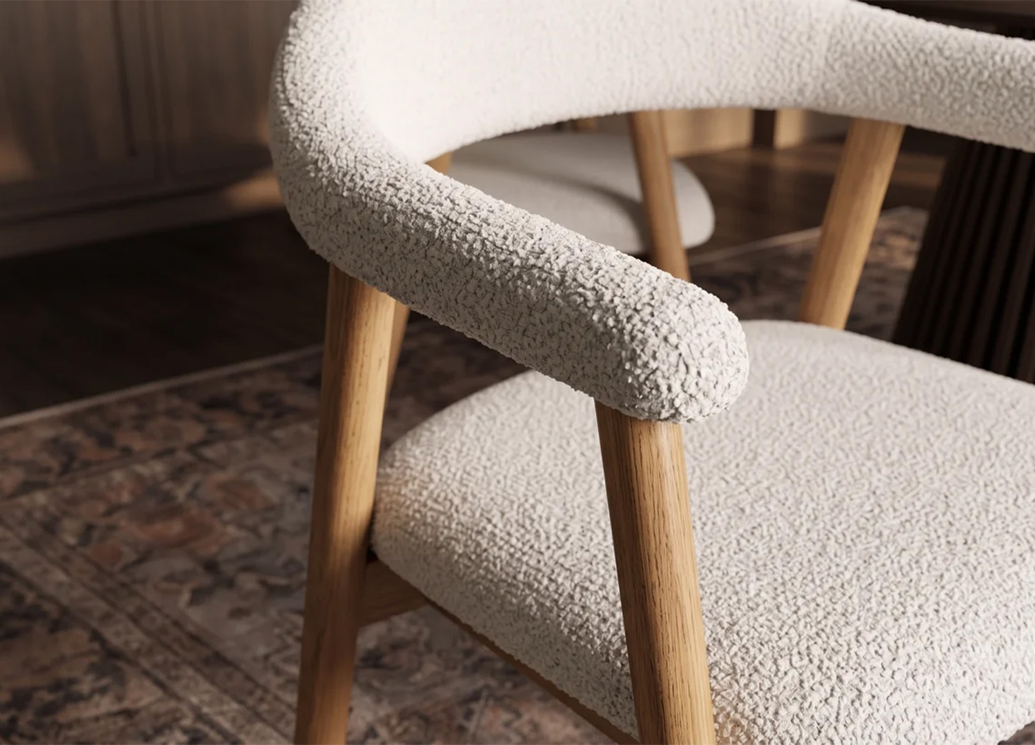 Gros plan sur l'accoudoir arrondi de la chaise ELVANO, son revêtement en tissu beige bouclé et son support en bois clair