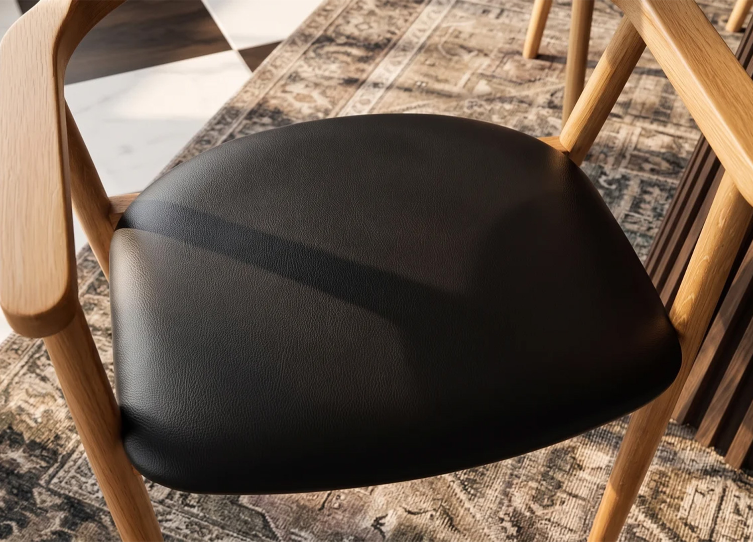 Vue de dessus de l'assise noire rembourrée de la chaise ELVANO, encadrée par ses accoudoirs en bois clair