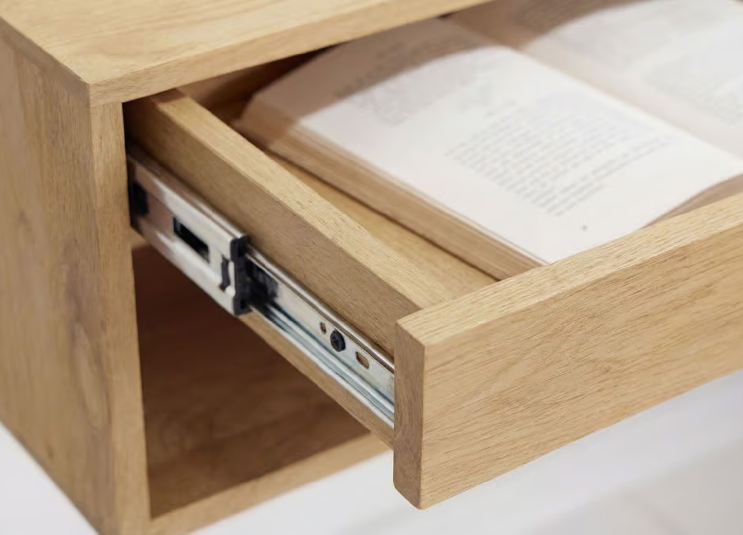 Détail des glissières métalliques du tiroir d’une table de chevet suspendue en bois clair