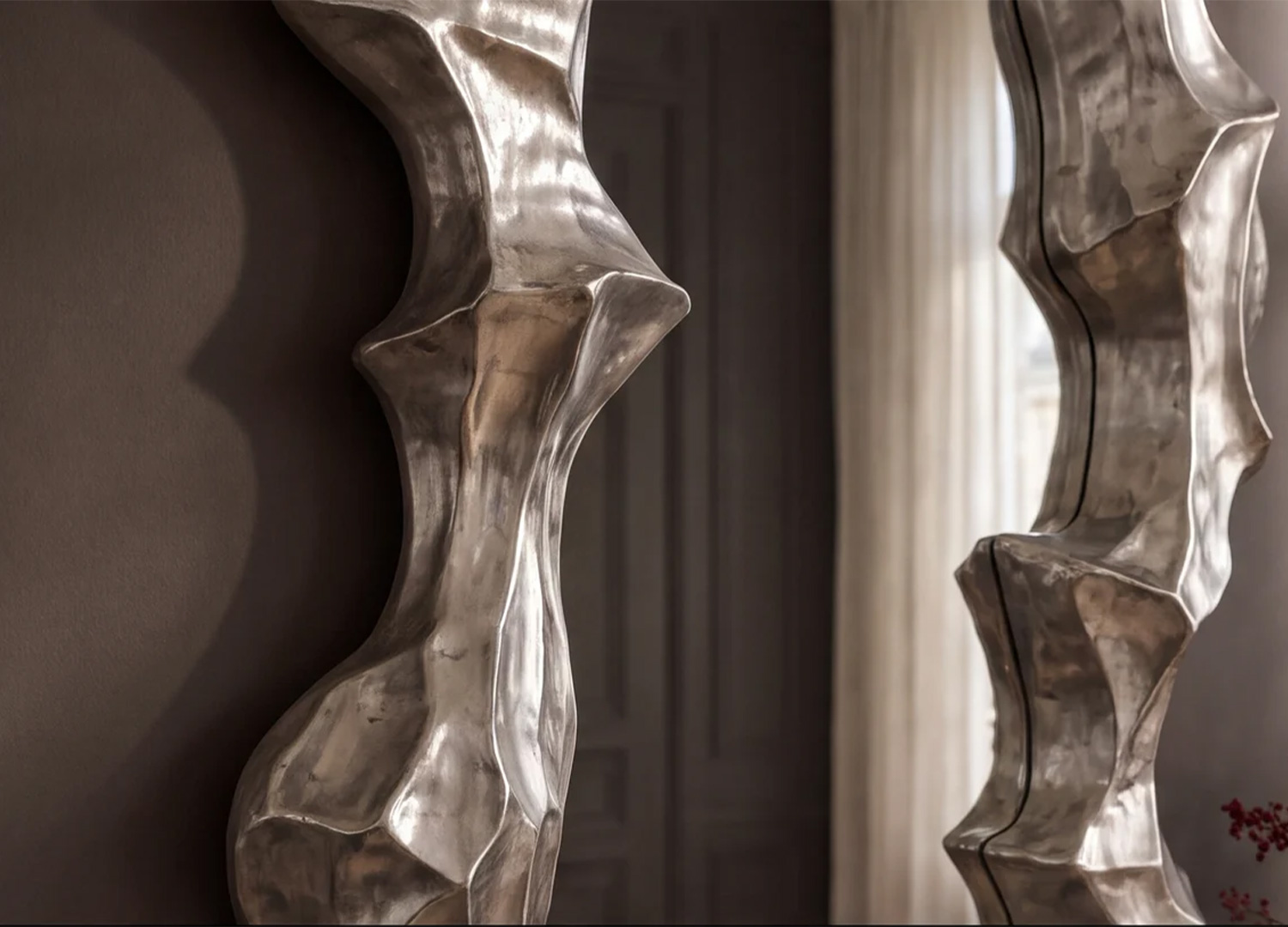 Vue rapprochée de l’épaisseur et des volumes sculptés du cadre argenté du miroir