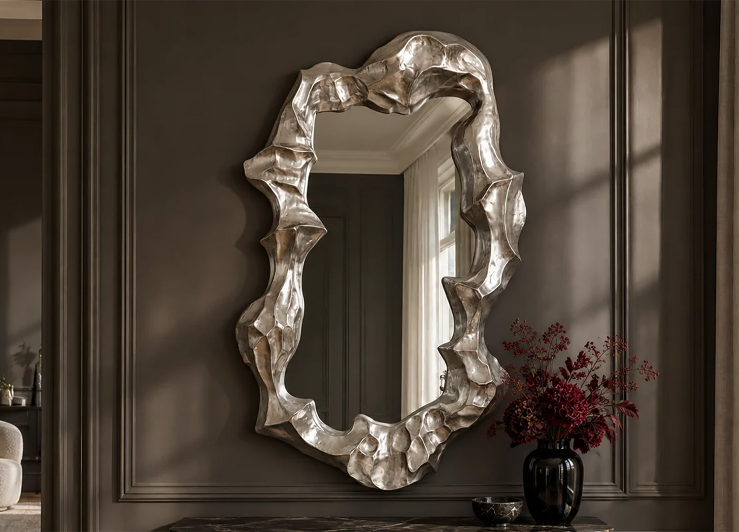 Vue de face d’un miroir mural argenté asymétrique à cadre épais sculpté