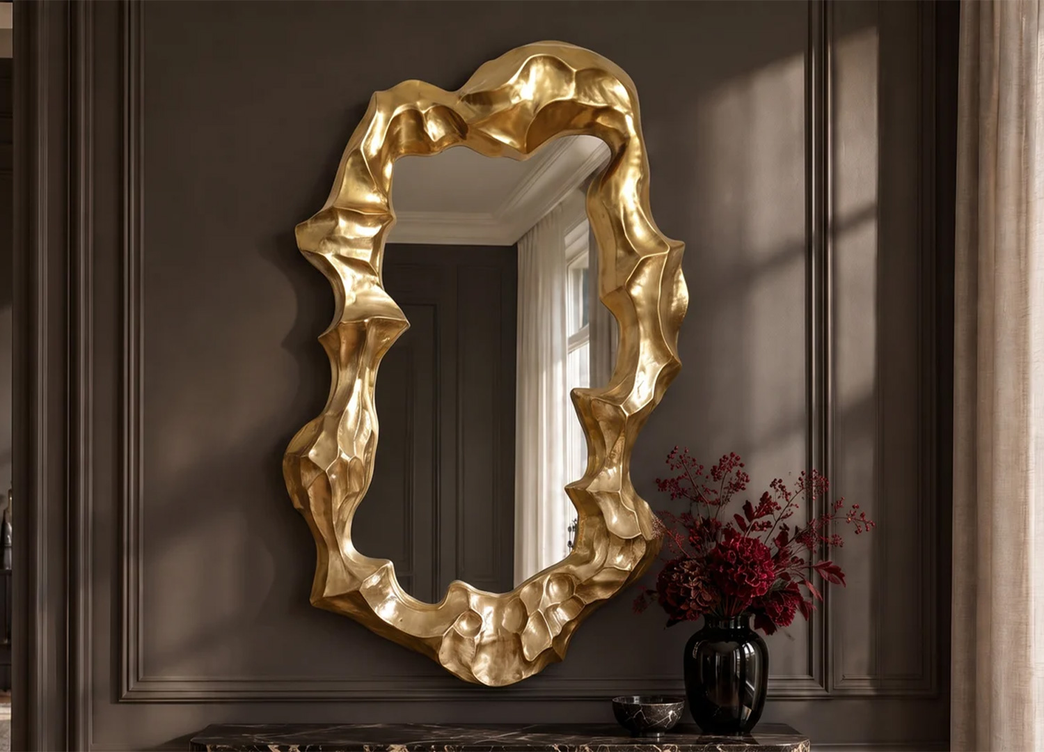 Grand miroir mural doré aux contours sculpturaux installé sur un mur sombre au-dessus d’une console
