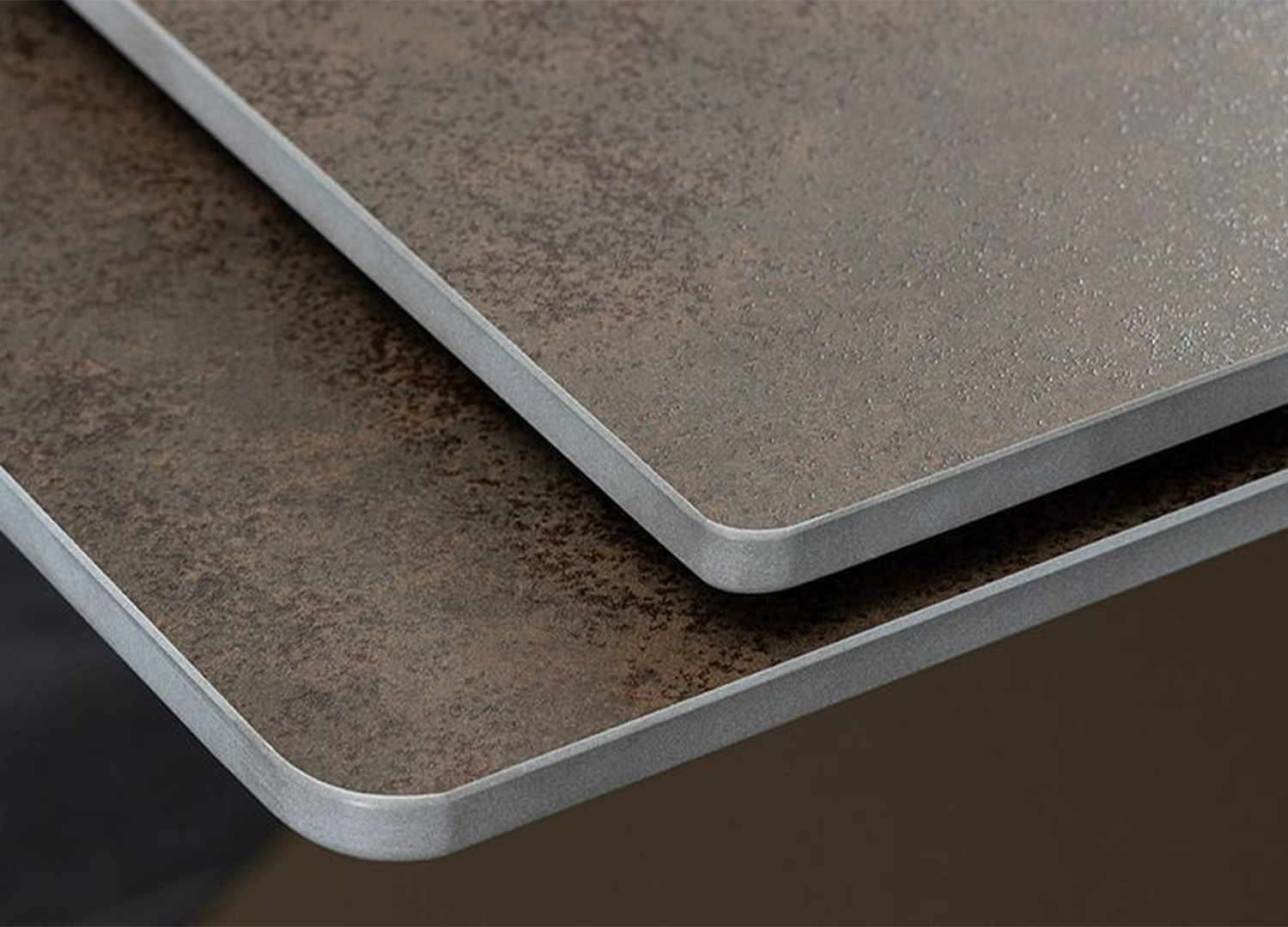 Gros plan sur les bords arrondis du plateau en céramique effet rouille de la table ASTRA