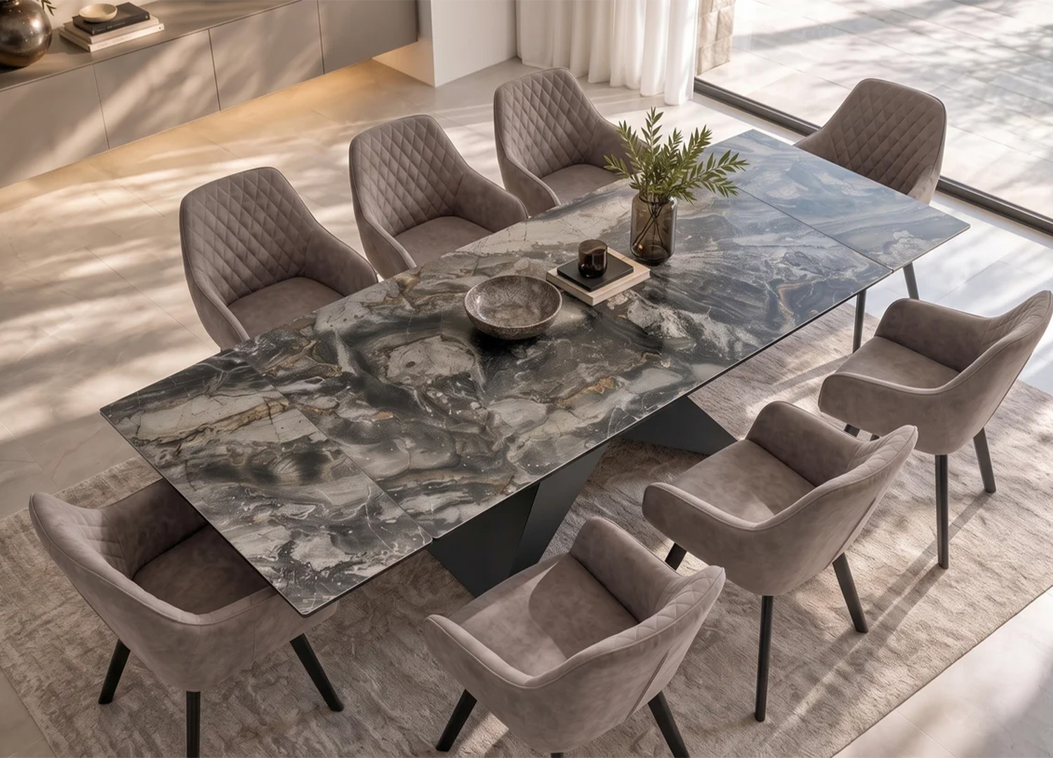 Vue plongeante de la grande table extensible en céramique gris effet marbre avec fauteuils capitonnés taupe