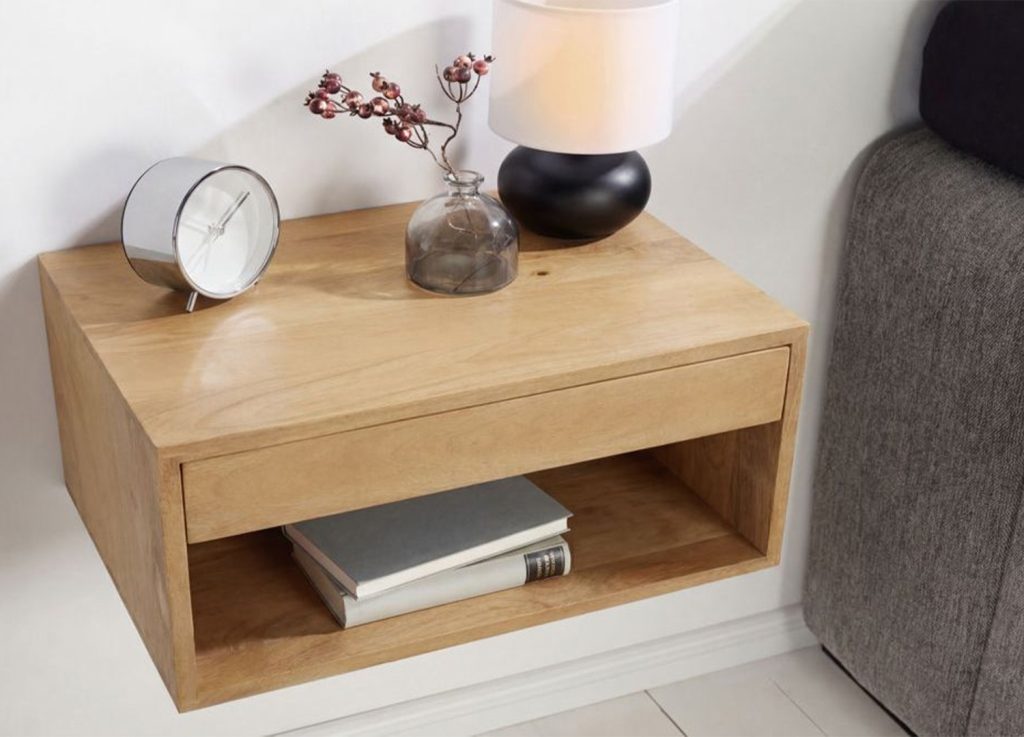 Table de chevet murale en bois naturel décorée d’une lampe, d’un réveil et de livres